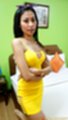 Standing beside bed arms folded wearing yellow dress