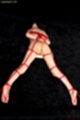 Lying on her front nude legs spread wide tied up with red shibari rope